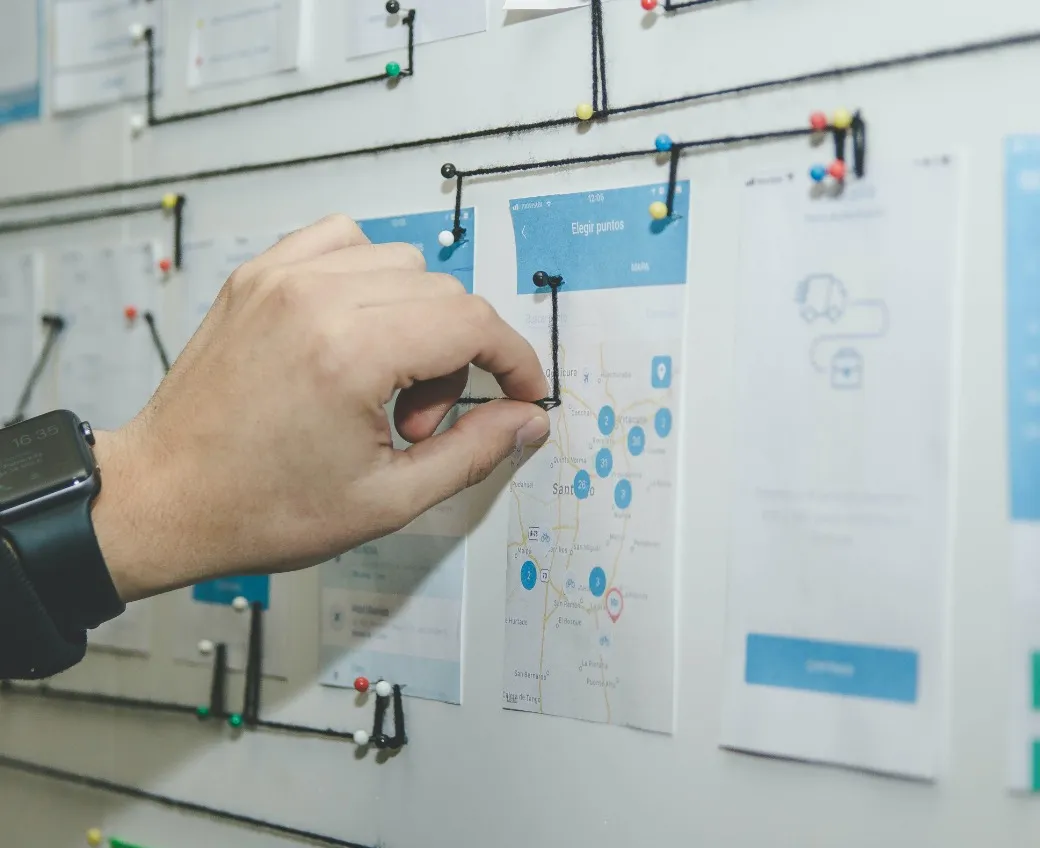 Man pinning notes and pictures to the wall and connecting them with string