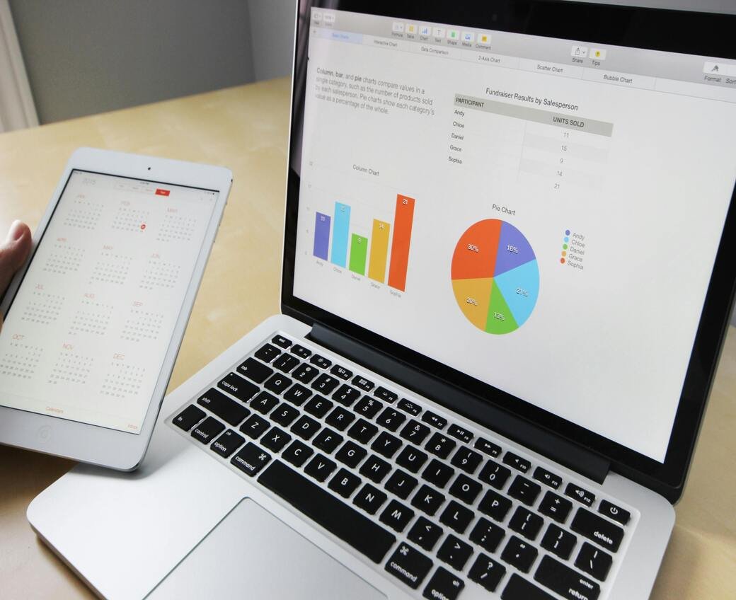 Laptop displaying charts and tables in a digital agency, with a phone showing an open calendar beside it.